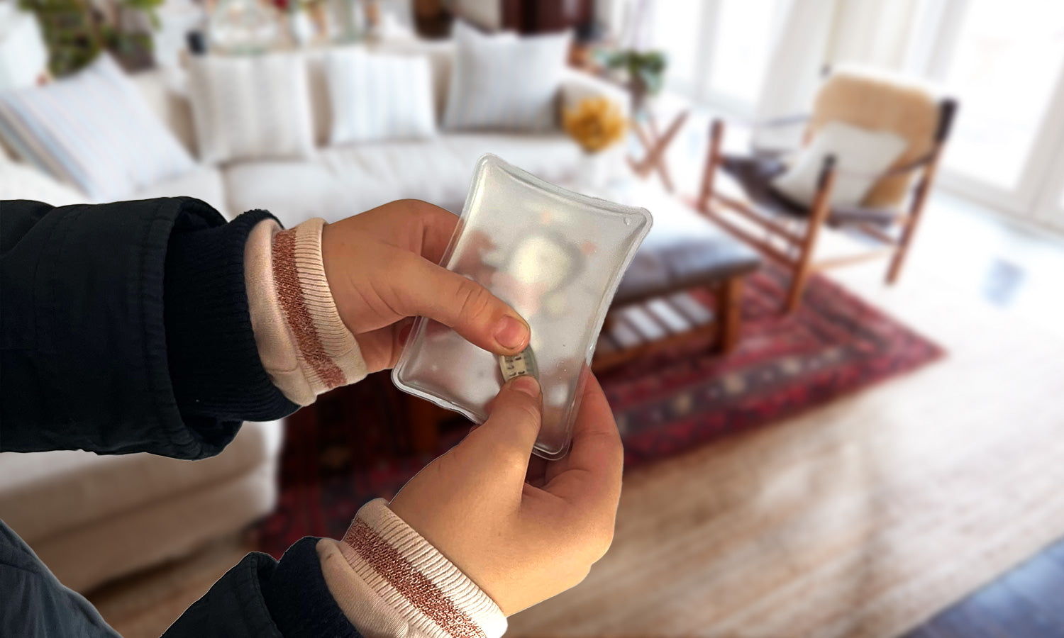 Ein Kind hält einen Handwärmer und drückt auf das Metallplättchen um den Handwärmer zu aktivieren